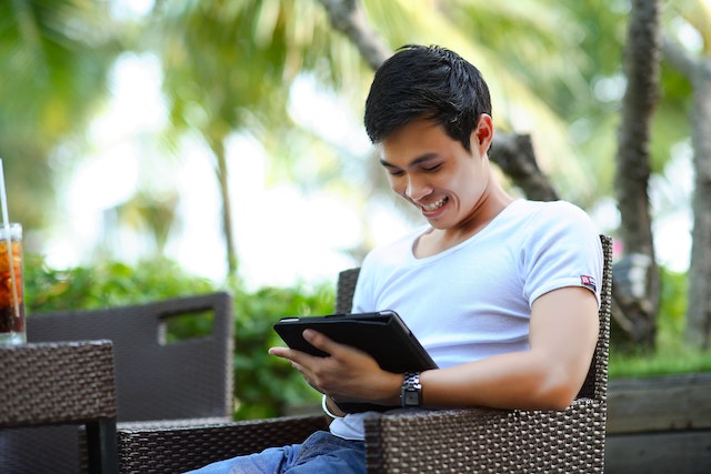 Man sat outside smiling at a tablet